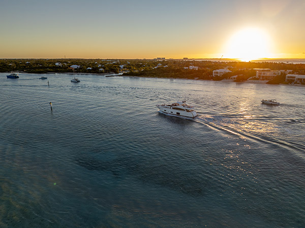 Drone aerial of luxury yacht arriving at Blue Haven Marina during sunset