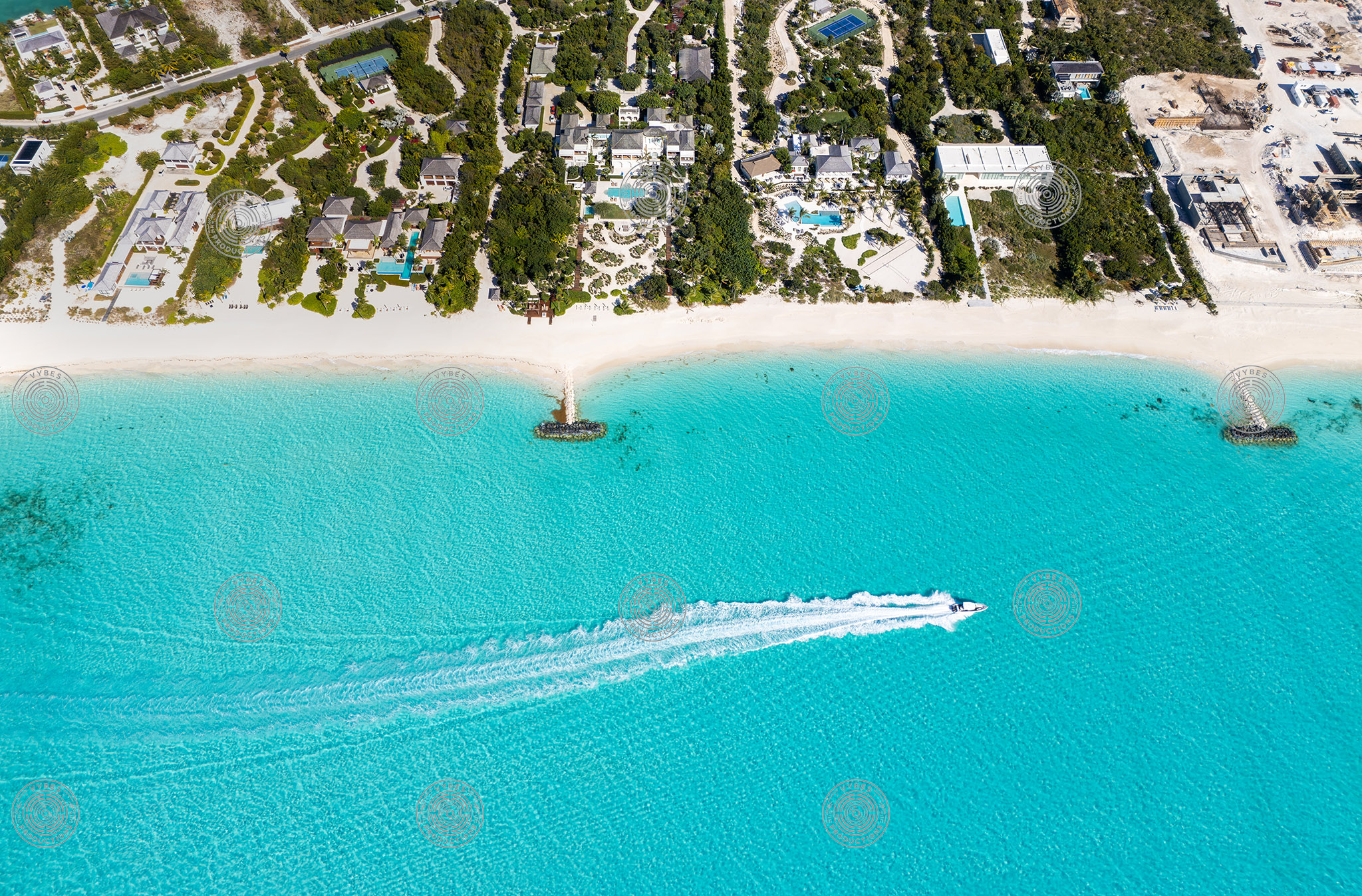 Drone view of boat passing luxury beachfront villas in Leeward