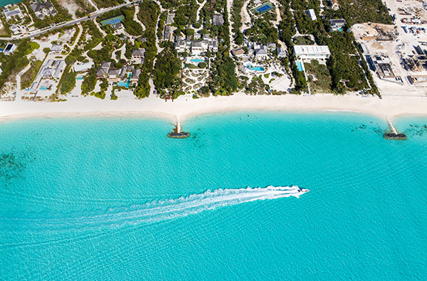Drone view of boat passing luxury beachfront villas in Leeward