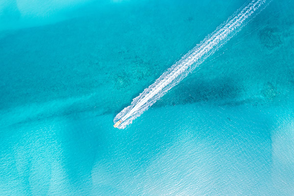 Drone shot of boat cruising across Grace Bay waters