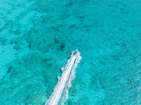 Tour boat leaving trail through clear Grace Bay water