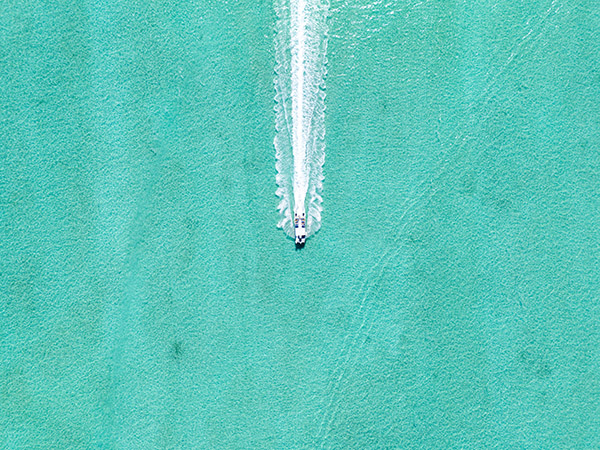 Tour boat leaving trail through shallow clear Grace Bay water