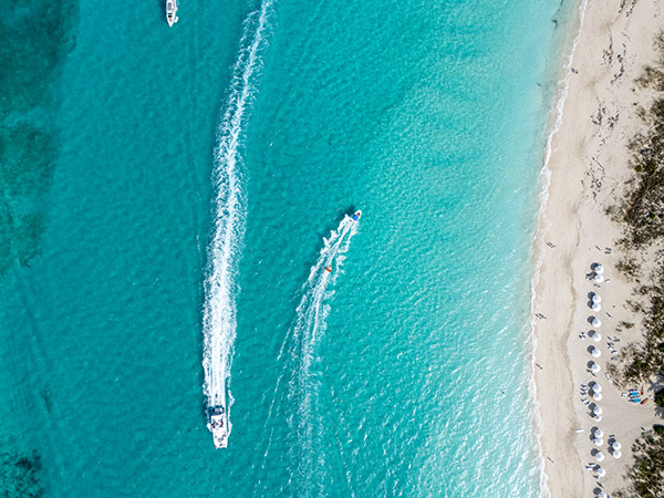 Top down drone shot of boat pulling tube off of Grace Bay Beach