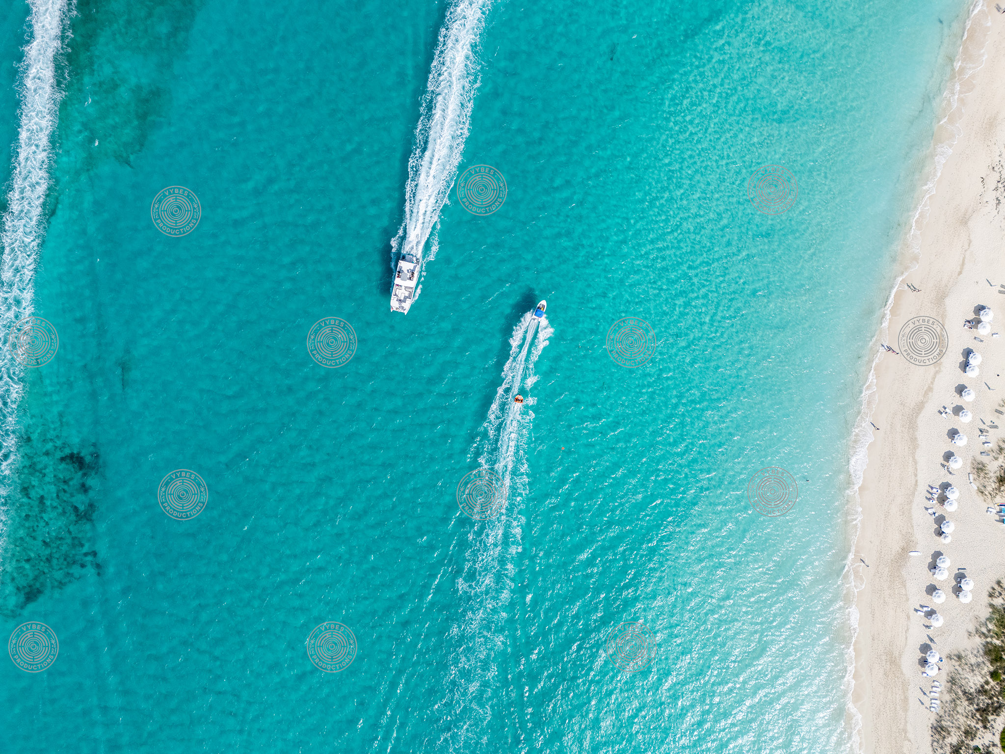 Top down drone shot of boat pulling tube off of Grace Bay Beach