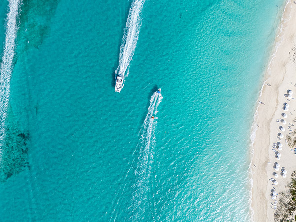 Top down drone shot of boat pulling tube off of Grace Bay Beach