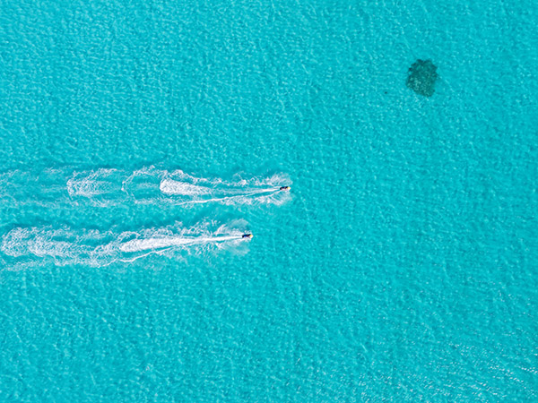 Jet Skis Racing Side by Side in Shallow Blue Water, Top-Down View
