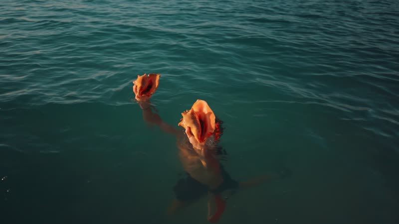 Snorkeler surfacing carrying conch shells