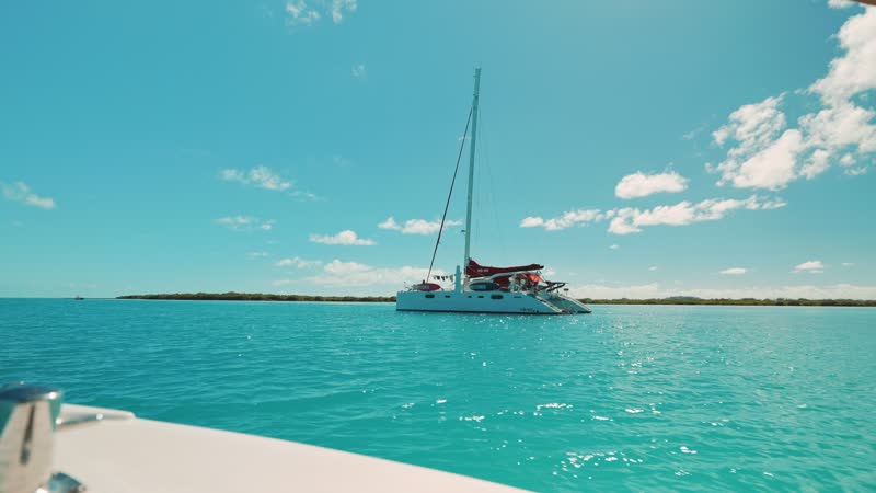 Following shot of luxury catamaran from small boat