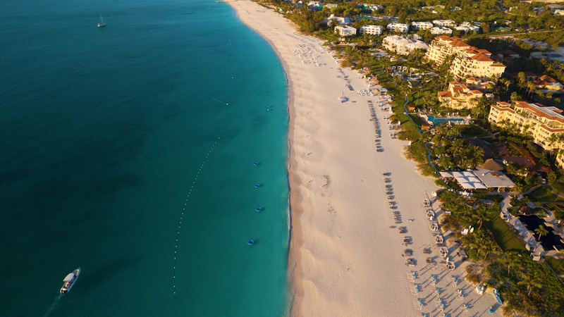 Long drone shot of Grace Bay Beach during sunset