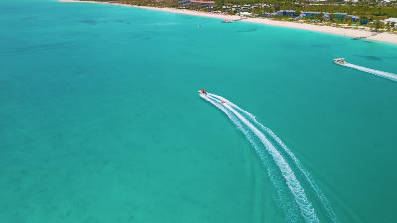 Drone shot of a boat pulling a tube near Grace Bay Beach
