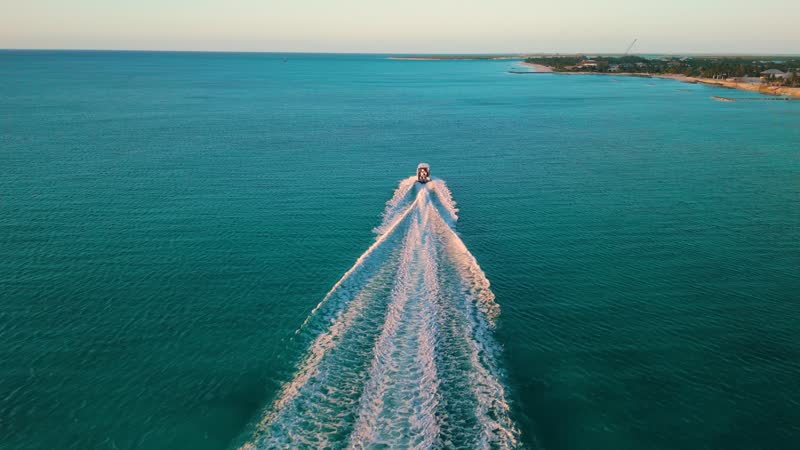 Golden hour drone shot of boat cruising off of Grace Bay Beach