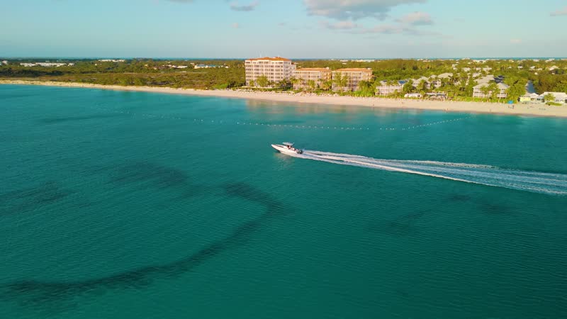 Golden hour drone shot of boat cruising off of Grace Bay Beach