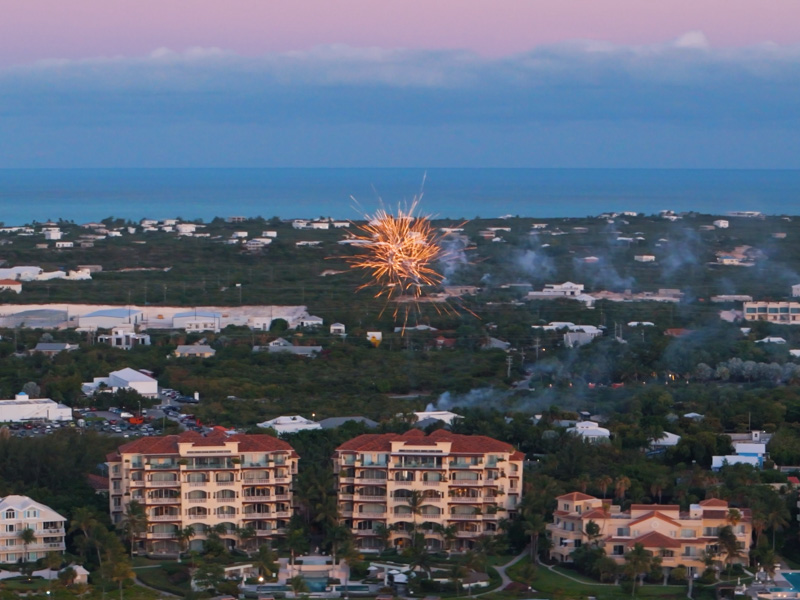 Zoom drone shot of fireworks behind grace bay resorts at sunset