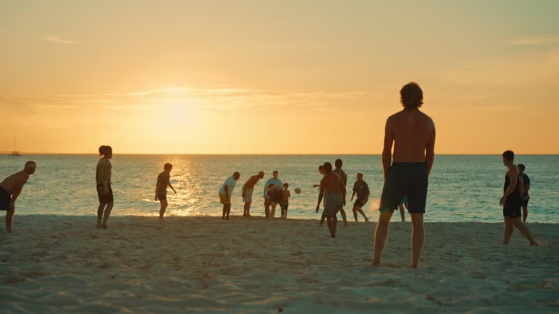 Slow-motion shot of tourists playing on Grace Bay Beach during sunset