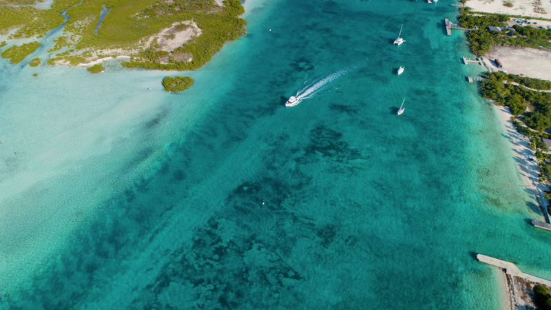 Aerial panning shot of boat gliding over deep turquoise waters in the Leeward Channel
