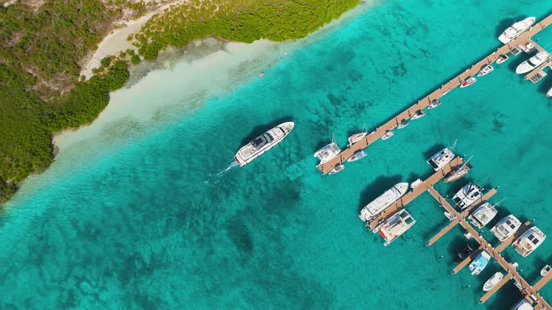 Drone shot of large luxury yacht moving past Blue Haven Marina