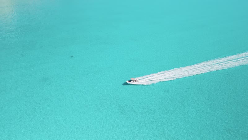 Drone shot following boat moving through vibrant Long Bay waters