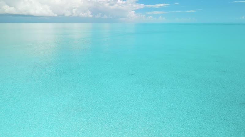 Moving drone shot of vibrant blue Long Bay waters