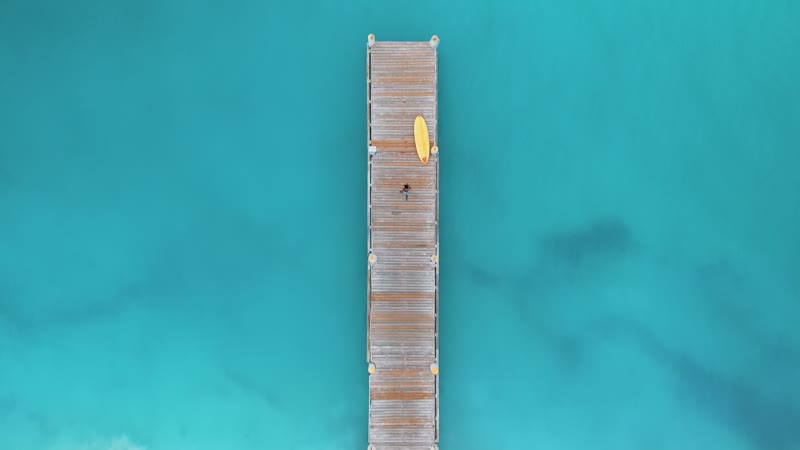 Drone shot following tourist dive into water along Grace Bay Beach